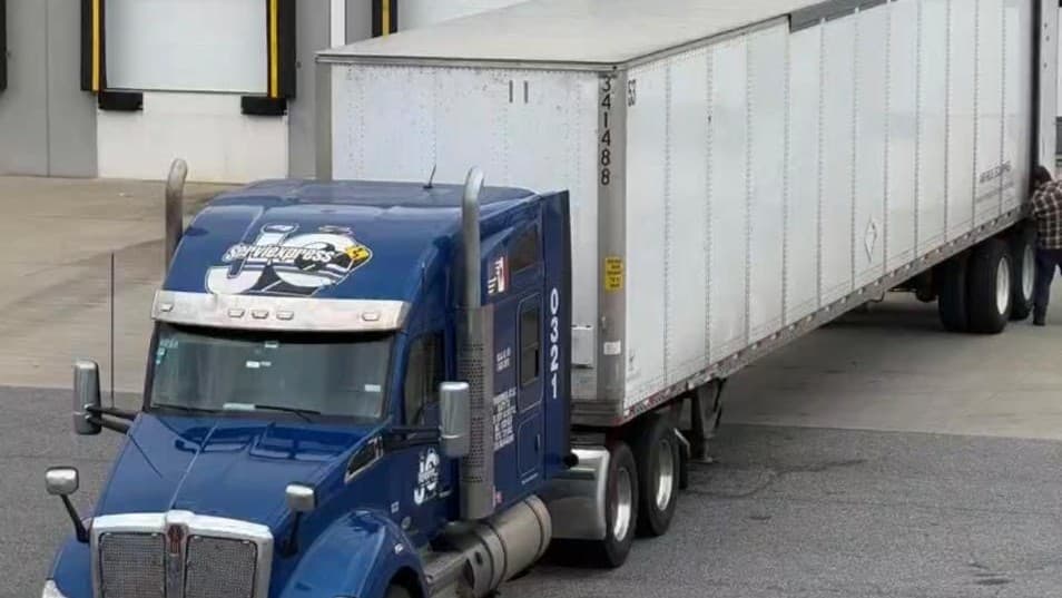 Tractocamión Kenworth de ServiExpress JC con caja seca de 53 pies cargando en un andén de distribución